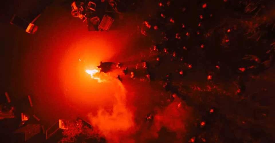 Alt: Batman holding a red flare leading a group of people though the flood